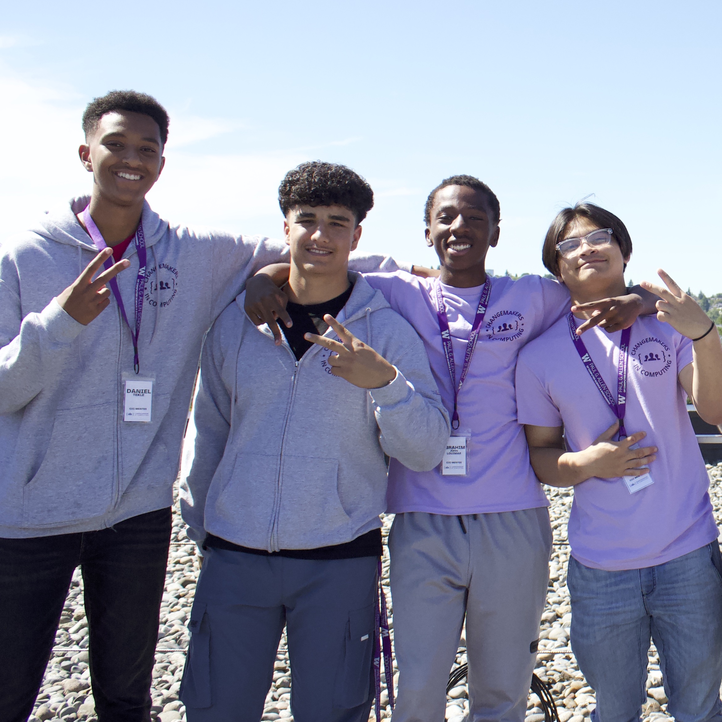 4 students with their arms around each other facing smiling towards the camera