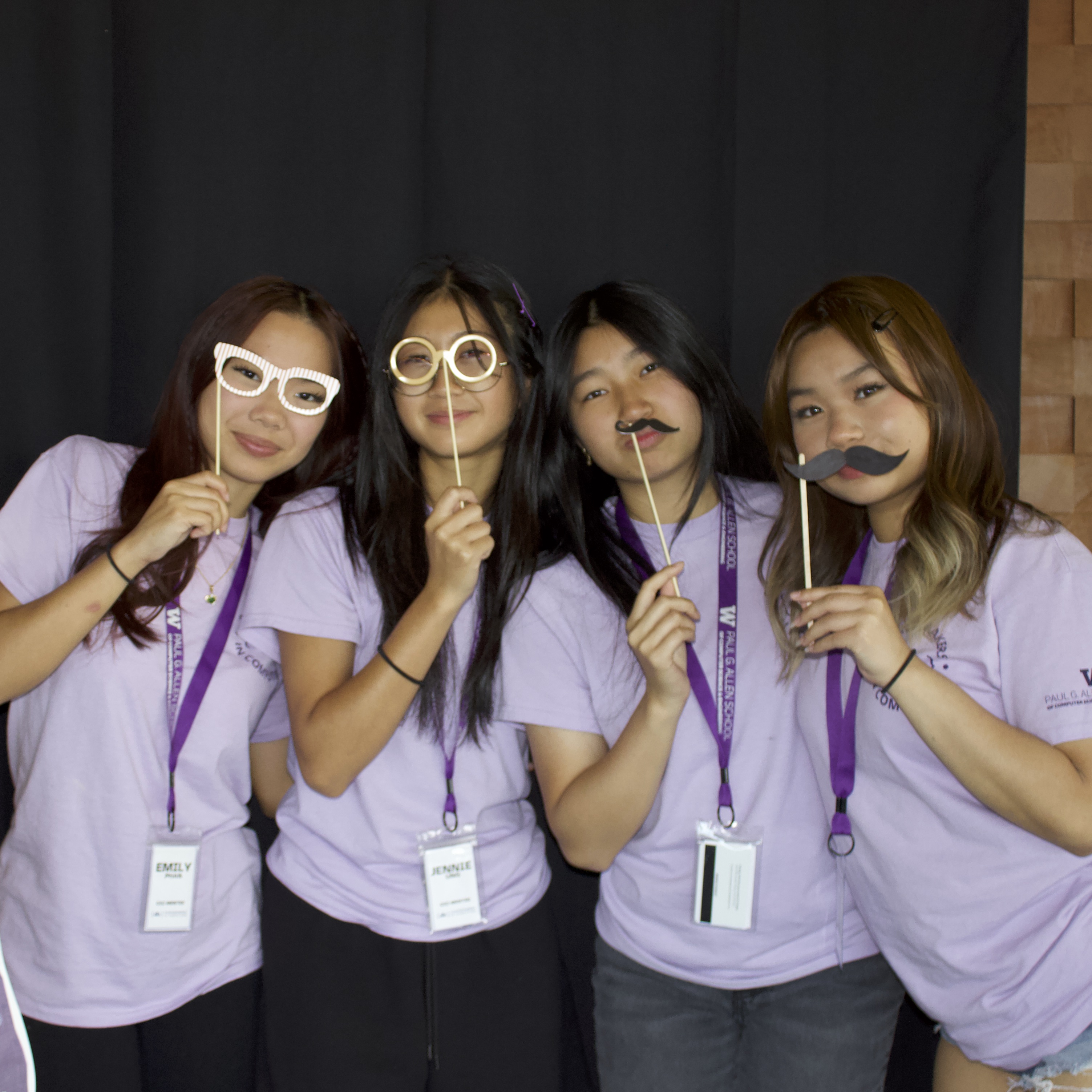 4 students posing with various photobooth props smiling at the camera